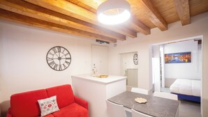 A modern room with a red sofa, a dining table, and a white cabinet. - Ca' Gritti (Venice)