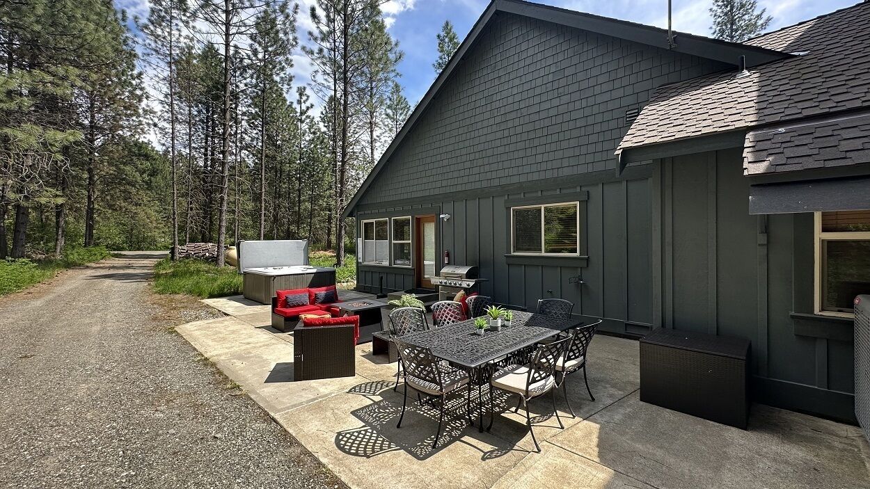 A house with a patio area featuring a grill, outdoor seating, and a table with chairs.