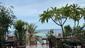 A terrace with wooden furniture, potted plants, and a view of the ocean. - SUNNY CANOPY (Hulhumalé)