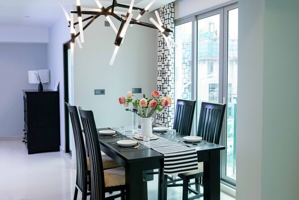 Ein moderner Essbereich mit einem schwarzen Tisch, weißen Tellern und einer Blumenvase.