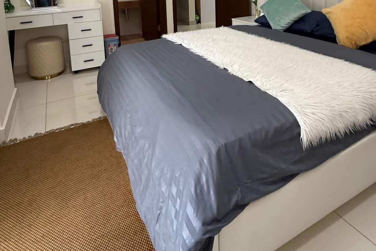 Un dormitorio con cama, escritorio, espejo y equipo de aire acondicionado.