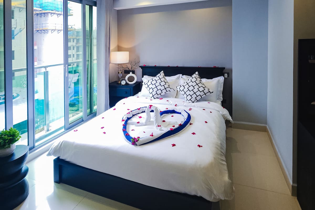 Un dormitorio moderno con una cama grande, un ventilador de techo y una mesita de noche con lámpara.