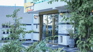 A modern hotel entrance with a glass door, potted plants, and a sign above the door. - SUNNY CANOPY (Hulhumalé)