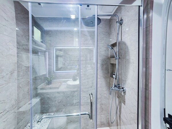 A glass-enclosed shower with a handheld showerhead and a wall-mounted faucet. - SUNNY CANOPY (Hulhumalé)