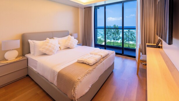 A modern hotel room with a large bed, a desk, and a view of the ocean. - SUNNY CANOPY (Hulhumalé)