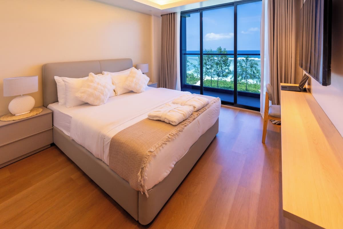 Una habitación de hotel moderna con una cama grande, un escritorio y vistas al océano.