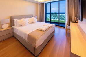 Ein modernes Hotelzimmer mit einem großen Bett, einem Schreibtisch und Meerblick.