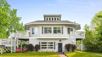 Une maison à deux étages avec un porche couvert, une petite terrasse et une porte d’entrée.