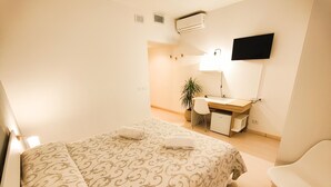 A bedroom with a bed, a desk, a chair, and a potted plant. - ALBERGO B&B TENESI (Manerba del Garda)