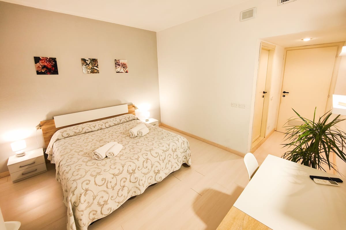 A hotel room with a bed, bedside tables, a desk, and a chair.