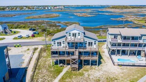 A coastal house with a large deck, a swimming pool, and a view of the water.