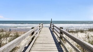 A wooden boardwalk leading to a beach with ocean views.