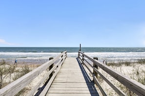 Walk along the boardwalk to the pristine beach with a clear view of the ocean and sandy shore.