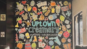A wall mural with various food and drink illustrations, the text "UPtown Creamery" and "small batch made from scratch" visible.