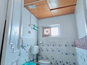 A bathroom with a toilet, a window, and a shower area. - Himalayan Bunker leh (Leh)