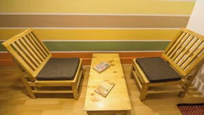 Two wooden chairs with cushions, a wooden table, and a striped wall in the background.