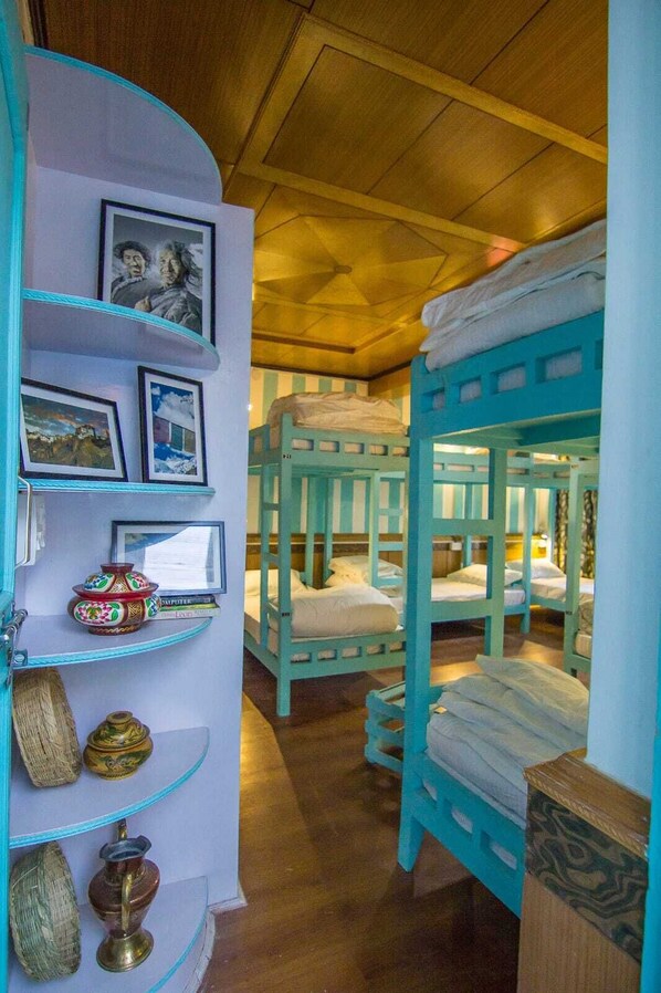 Bunk beds with a shelf displaying framed photos and decorative items. - Himalayan Bunker leh (Leh)