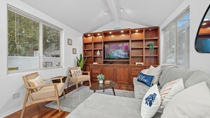 Un salon moderne comprenant un meuble de rangement en bois pour l’équipement audiovisuel, un canapé, une table basse et un fauteuil.