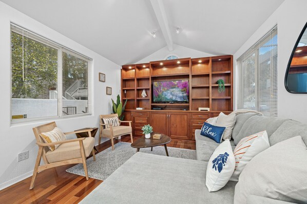 A modern living room with a wooden entertainment unit, a sofa, a coffee table, and a chair.