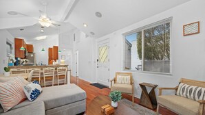 Un salon spacieux avec un canapé, une table basse et un coin repas comprenant des chaises, et une cuisine en arrière-plan.