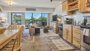 Eine moderne Küche mit Holzausziehtüren, einem Essbereich mit Tisch und Stühlen sowie eine große Schiebeglas-Tür, die auf einen Balkon führt.
