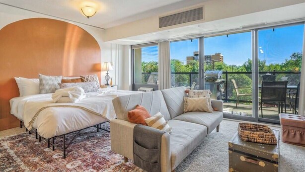 Ein modernes Schlafzimmer mit einem großen Bett, einer Couch und einem Balkon mit Blick.
