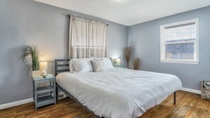 A bedroom with a bed, nightstand, lamp, and window.