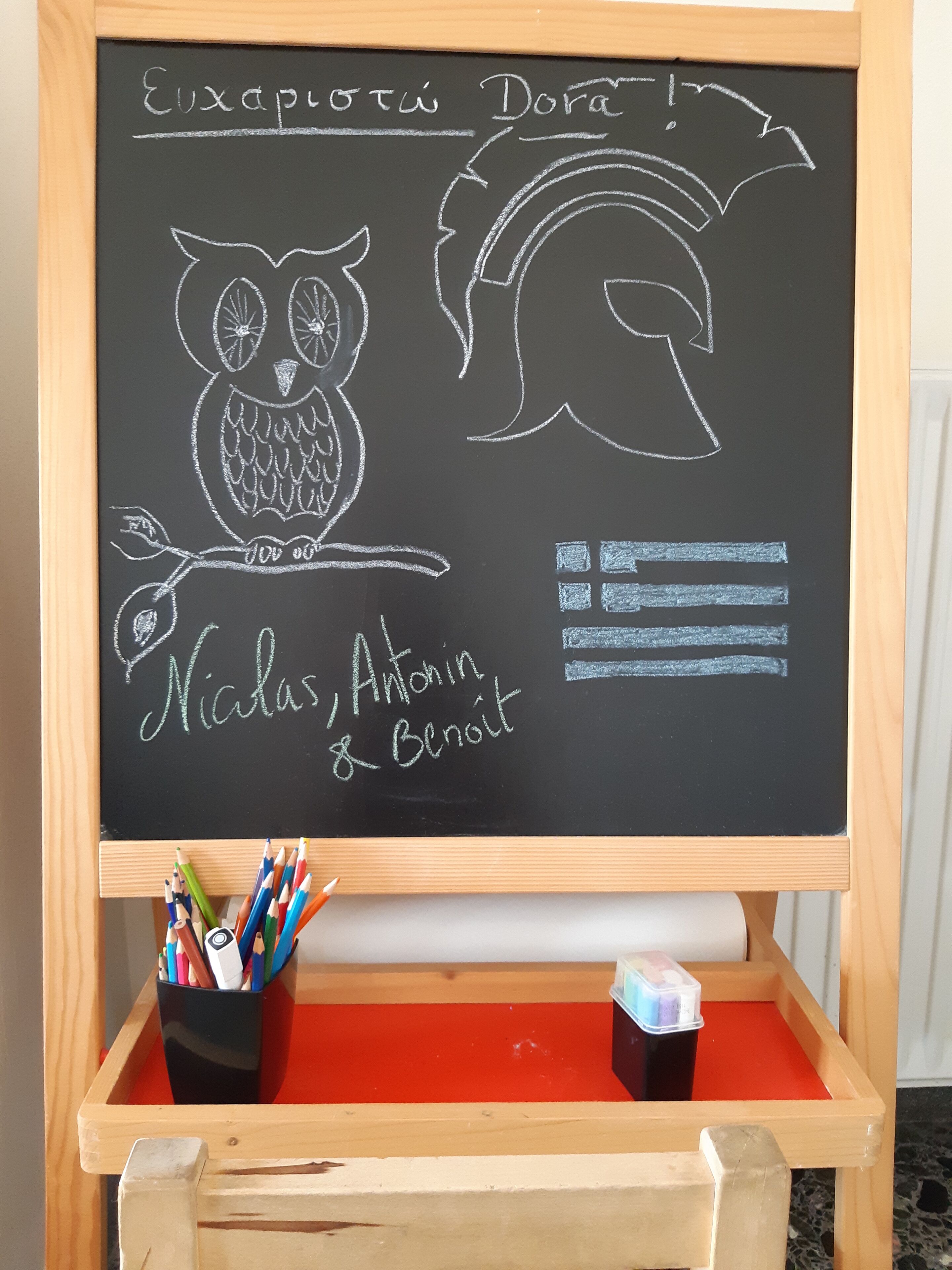 A chalkboard with drawings of an owl and a helmet, and names written below.