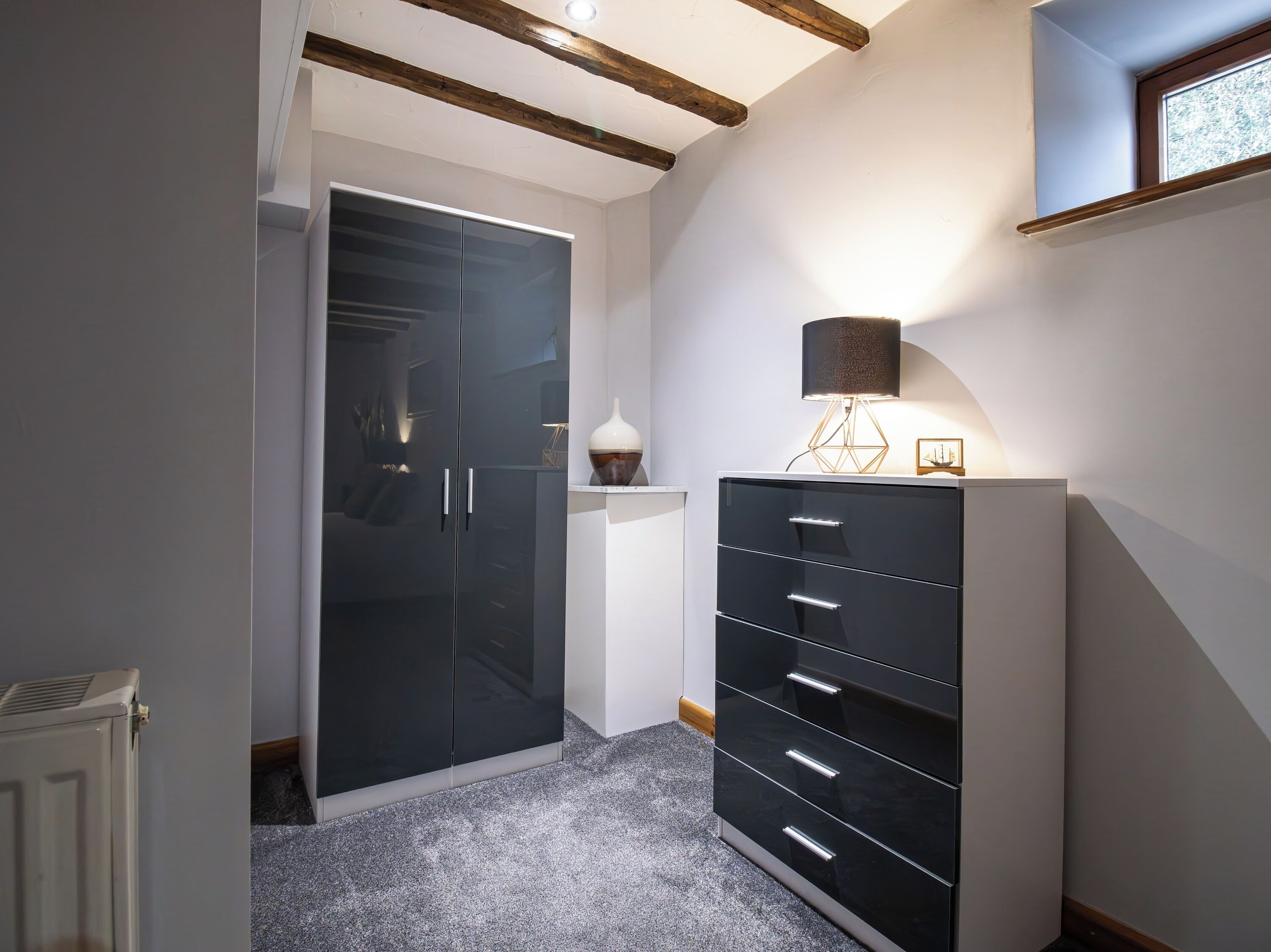 A hallway with a black wardrobe, a white cabinet, and a lamp.