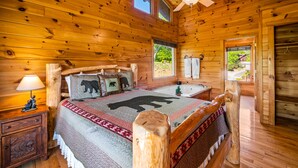 A wooden cabin bedroom with a bed, a nightstand, a ceiling fan, and a window. - Great location! Hot Tub Resort Pool Arcade, Outdoor Firepit, Free Attractions (Pigeon Forge)