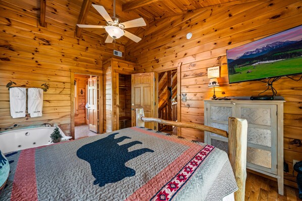 A wooden cabin interior with a bed, a television, a bathroom, and a staircase. - Great location! Hot Tub Resort Pool Arcade, Outdoor Firepit, Free Attractions (Pigeon Forge)