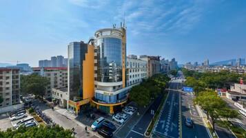 A multi-story hotel with a modern design, featuring a curved glass facade and a prominent orange section.