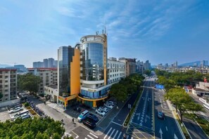 A multi-story hotel with a modern design, featuring a curved glass facade and a prominent orange section. - Xinhui Hotel (Zhoushan)