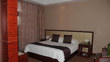 Una habitación de hotel con una cama grande, una mesita de noche, una silla y una pequeña mesa con una planta.