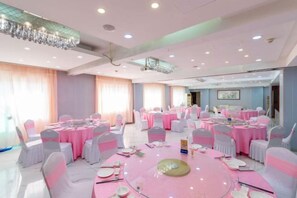 A banquet hall with round tables, chairs, and a chandelier. - Xinhui Hotel (Zhoushan)