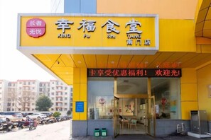 A yellow building with a sign that reads 'XING FU SHI TAING' and 'Cardholder welcome, enjoy the benefits!' - Xinhui Hotel (Zhoushan)