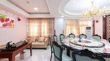 A dining area with a round table, chairs, and a chandelier.