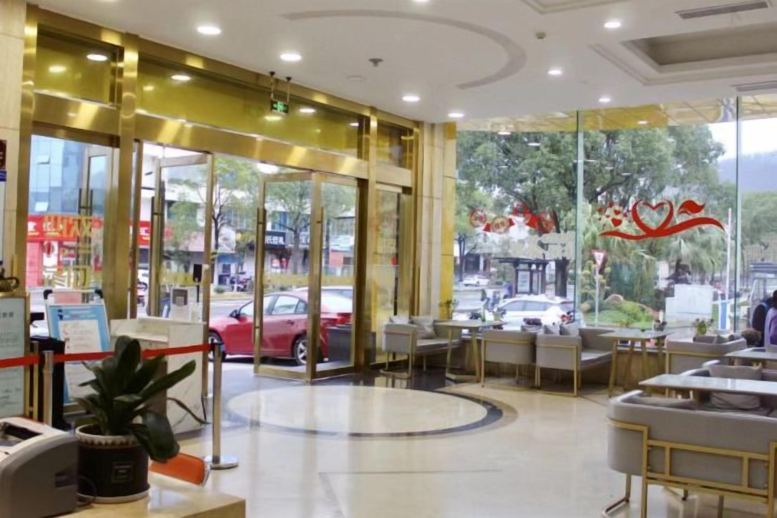 A hotel lobby with a reception desk, seating area, and large windows.