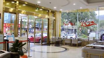A hotel lobby with a reception desk, seating area, and large windows.