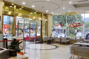 A hotel lobby with a reception desk, seating area, and large windows. - Xinhui Hotel (Zhoushan)