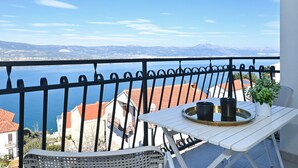 A balcony with a table and chairs, overlooking a body of water and distant mountains. - Grigic 4, modern 1 bedroom apartment (Mastinka)