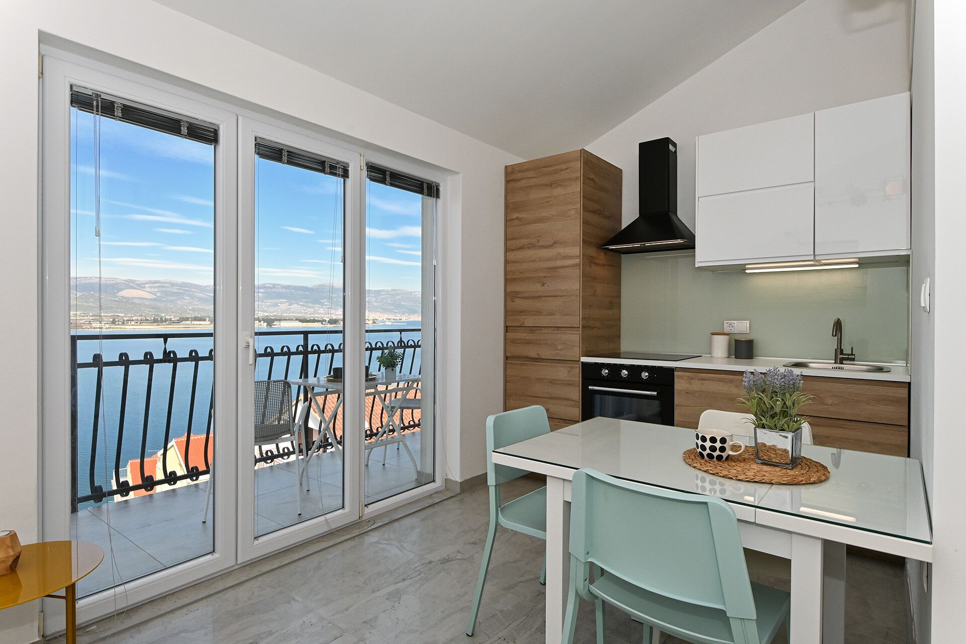 Eine moderne Küche mit Meerblick, ein Essbereich mit Stühlen und ein Balkon mit Geländer.