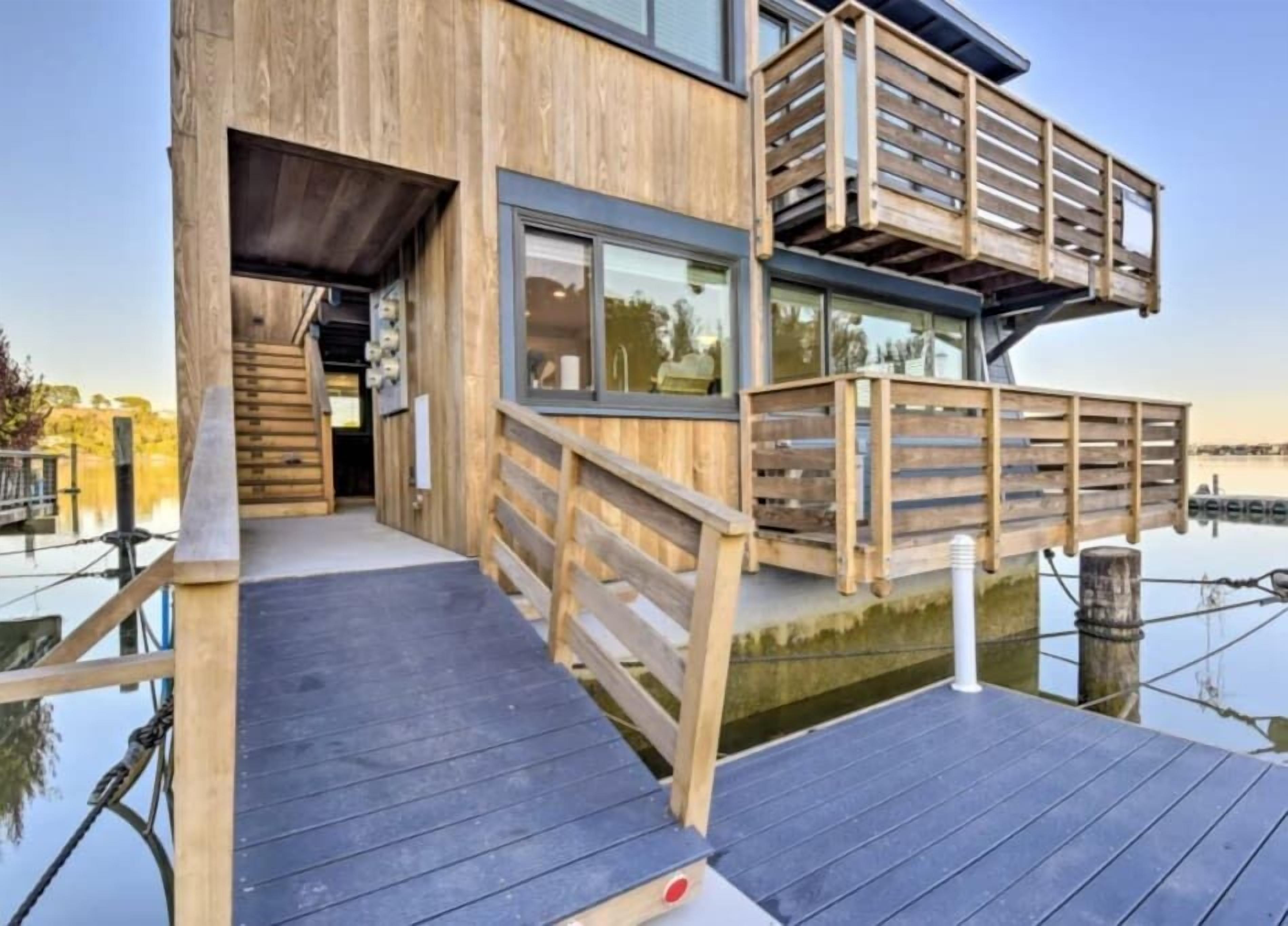 A wooden houseboat with a deck and a small entrance.