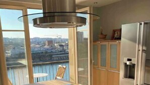Una cocina moderna con una isla central, electrodomésticos de acero inoxidable y vistas a la ciudad.