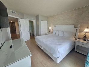 Un dormitorio con cama, mesitas de noche, lámpara, espejo y armario.