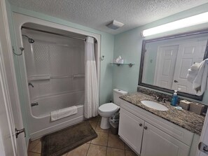 A bathroom with a bathtub, toilet, sink, and mirror.