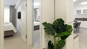 A modern hotel room with a bed, a TV, and a plant.