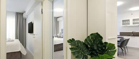 A modern hotel room with a bed, a TV, and a plant.