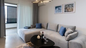 A modern living room with a sectional sofa, a round black coffee table, and a ceiling light fixture.