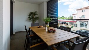 A dining area with a wooden table and chairs, a potted plant, and a view of the outside.